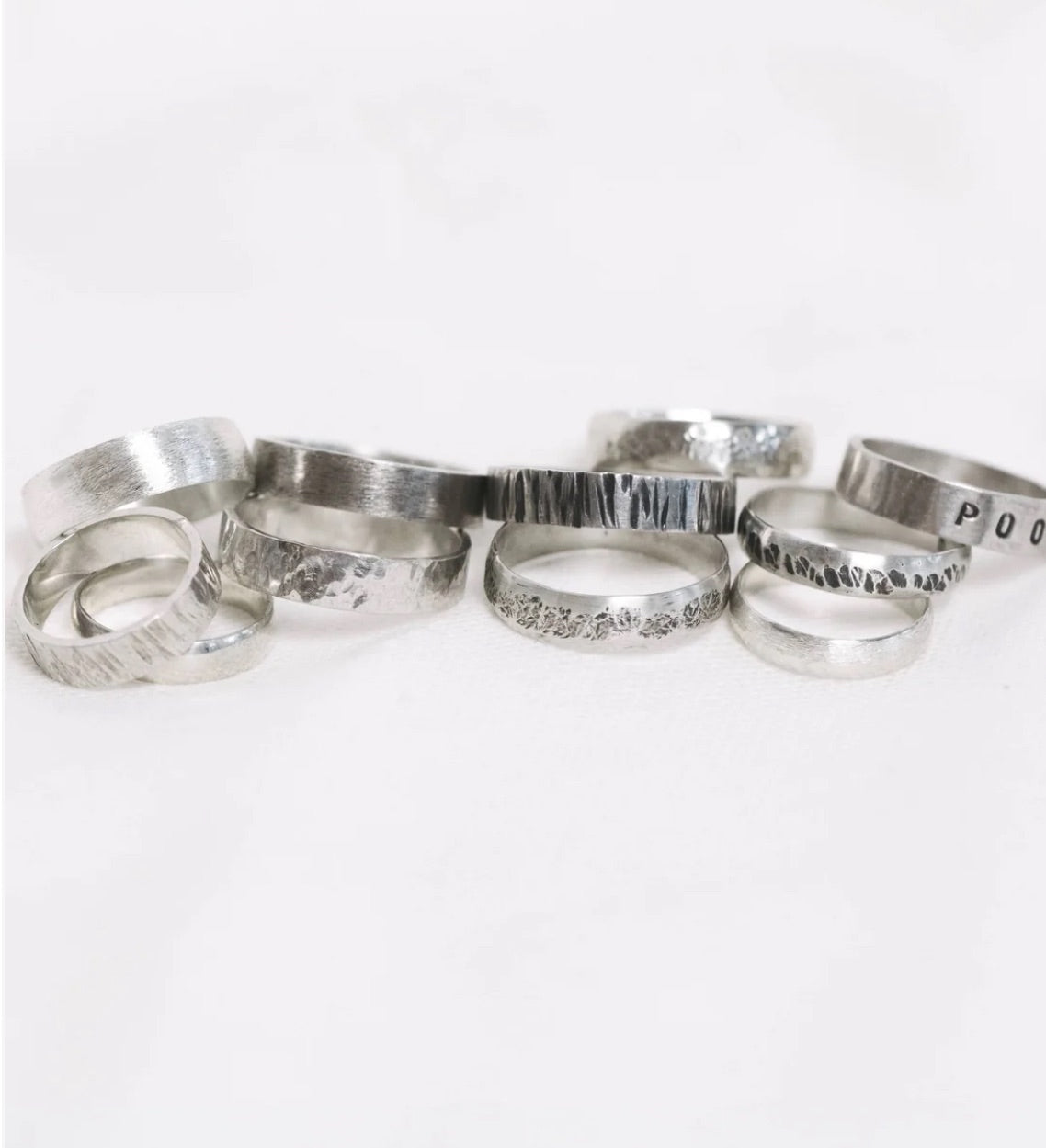 A collection of silver rings featuring various intricate designs displayed together.