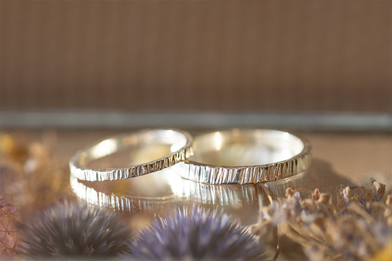 Two wedding rings resting on a glass table, reflecting light and symbolizing love and commitment.