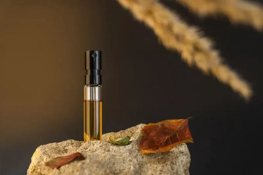 A small bottle of amber perfume placed on a stone surface, surrounded by autumn leaves, with warm lighting highlighting the golden fragrance