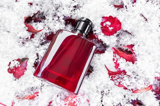 Red perfume bottle surrounded by winter elements like snow and leaves, highlighting how to choose a seasonal perfume for colder months.